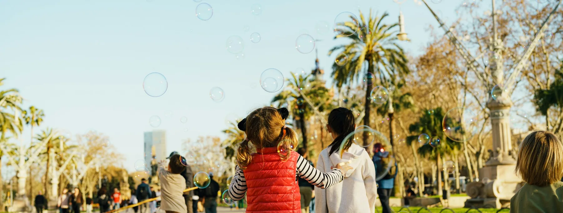 Niñas y niños jugando con pompas de jabón en un parque de Barcelona