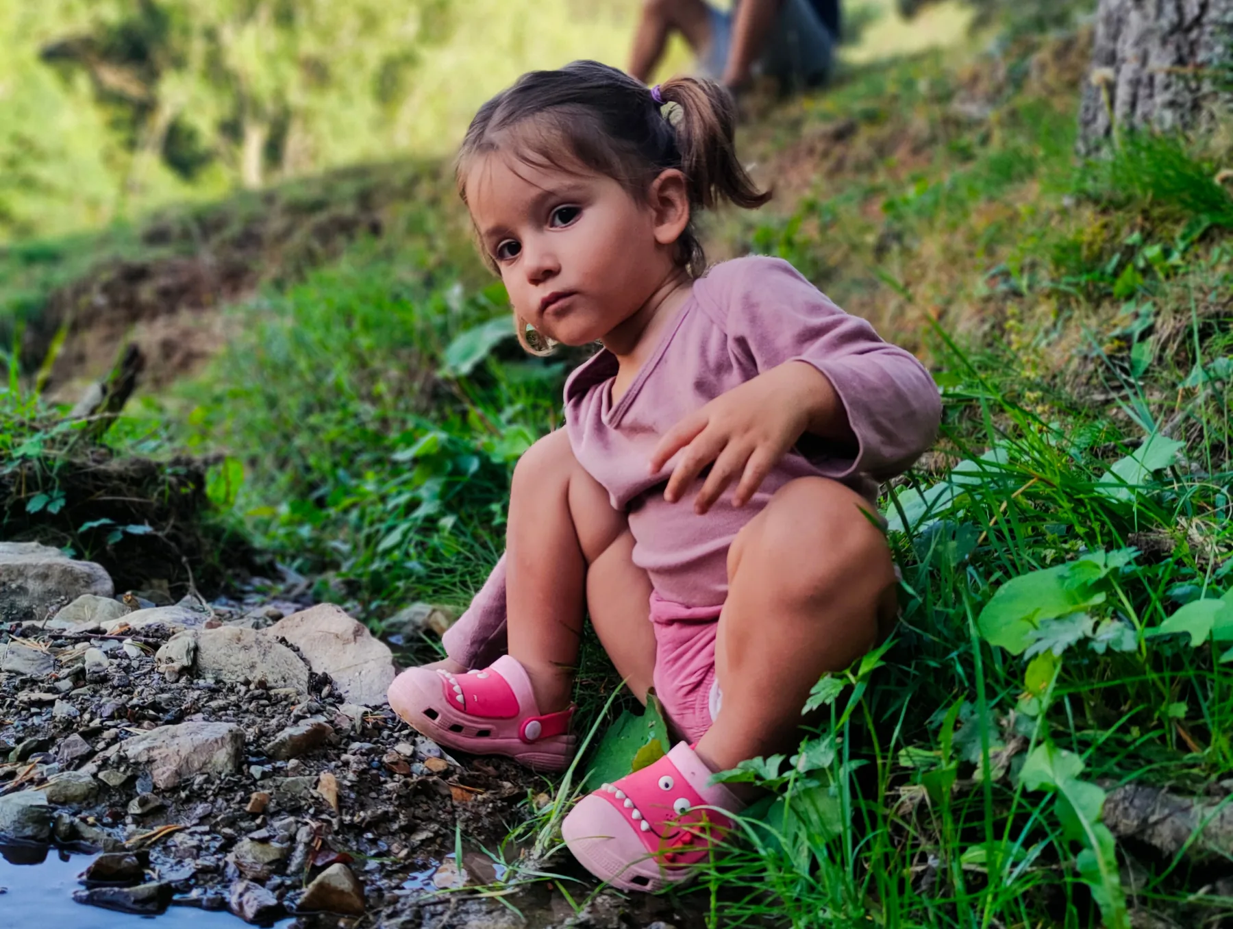 Niña observando el agua y las piedras de un arroyo en La Molina