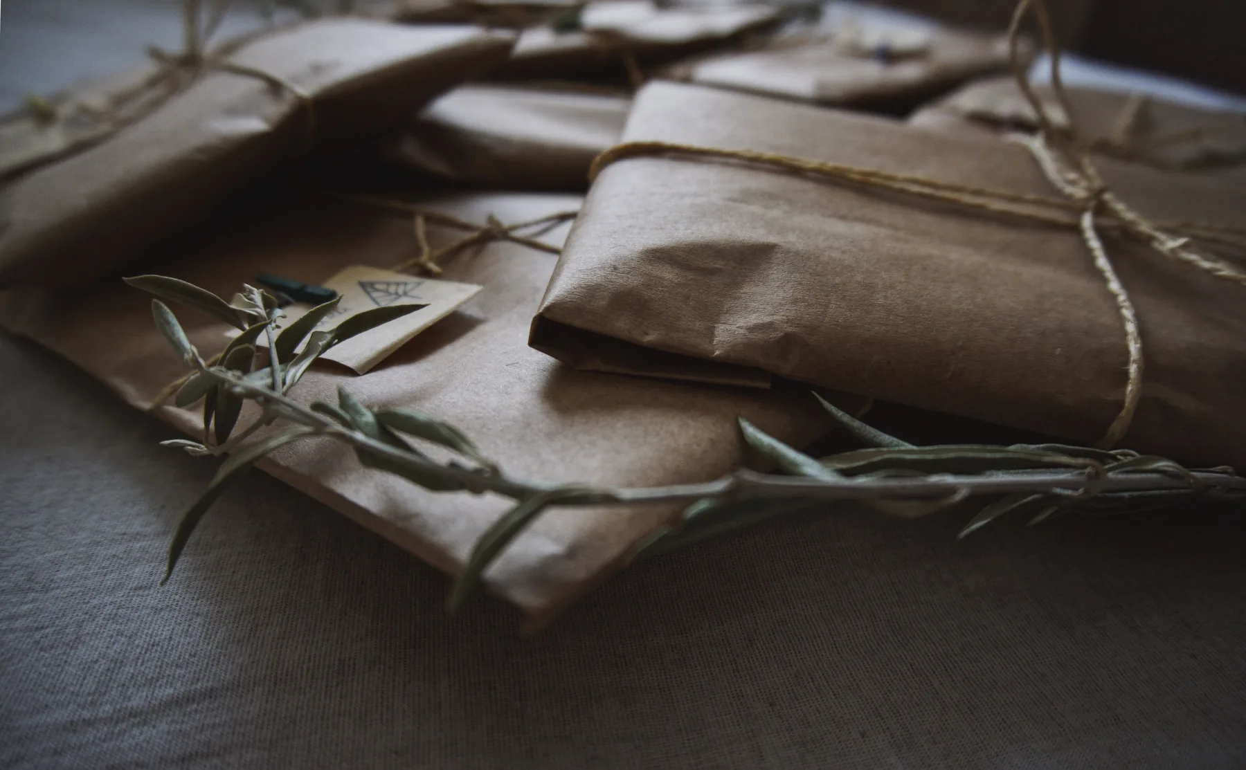 Paquetes de papel kraft atados con cuerda y ramas de olivo